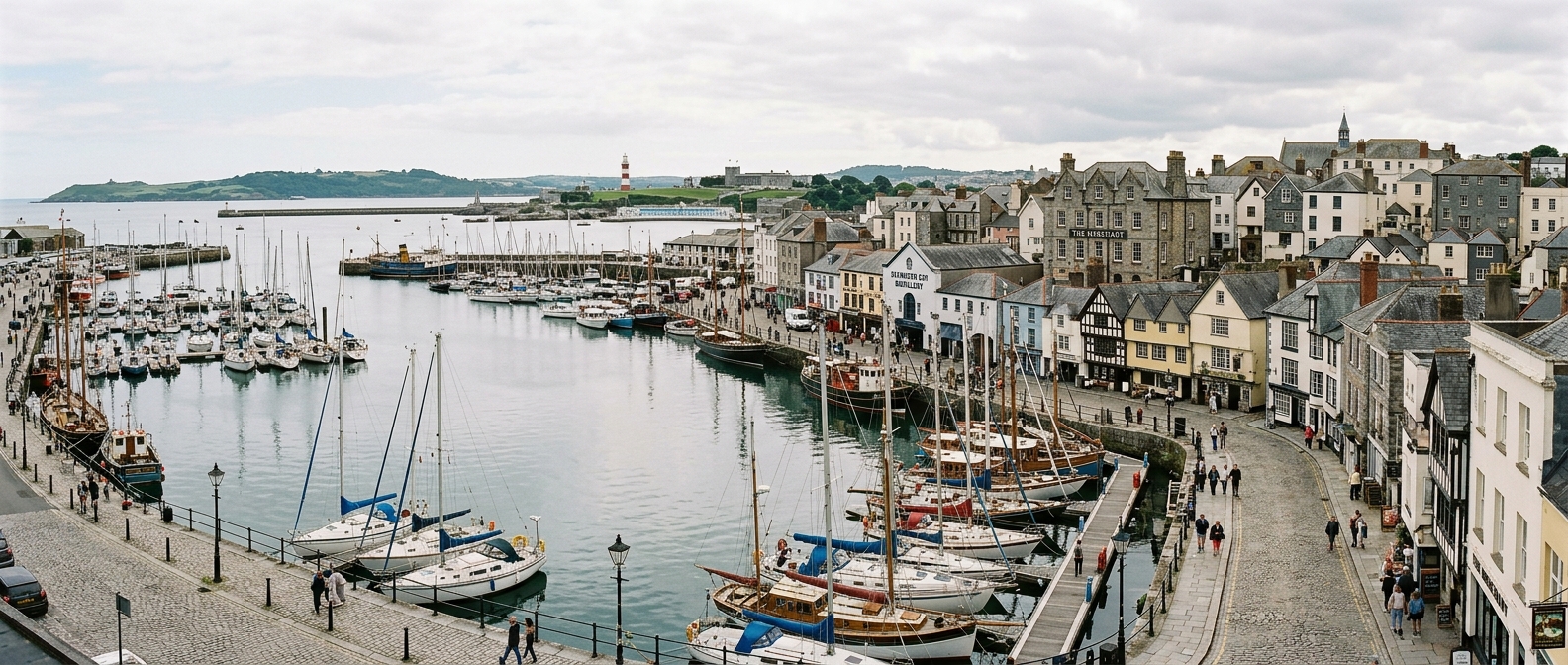 Plymouth waterfront panoramic view with historic harbour, Barbican area, and sailing boats on calm waters under soft English sky, with The Merchant building visible on St Andrew Street