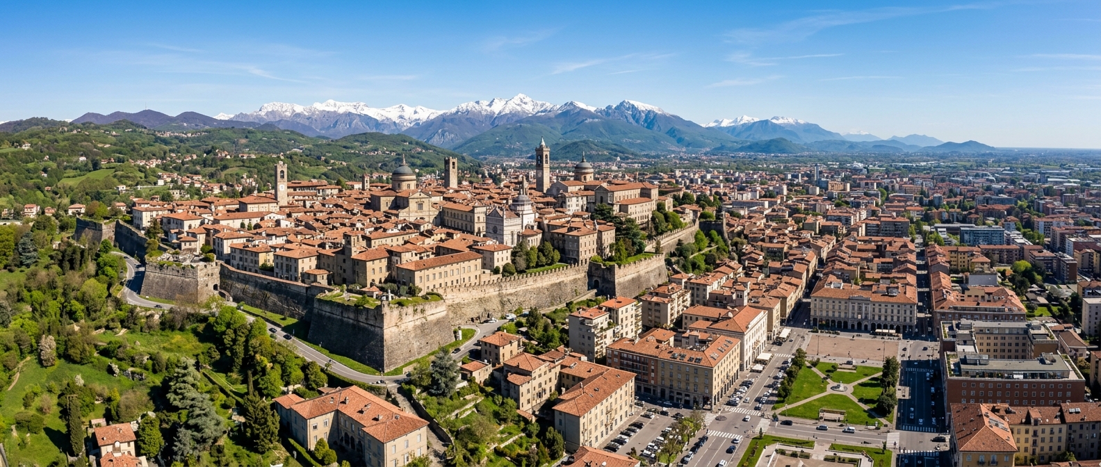 Panoramic view of Bergamo Italy, divided into Città Alta upper medieval town with Venetian walls and Città Bassa modern lower city, snow-capped Alps in background, terracotta rooftops, green hills, clear blue sky